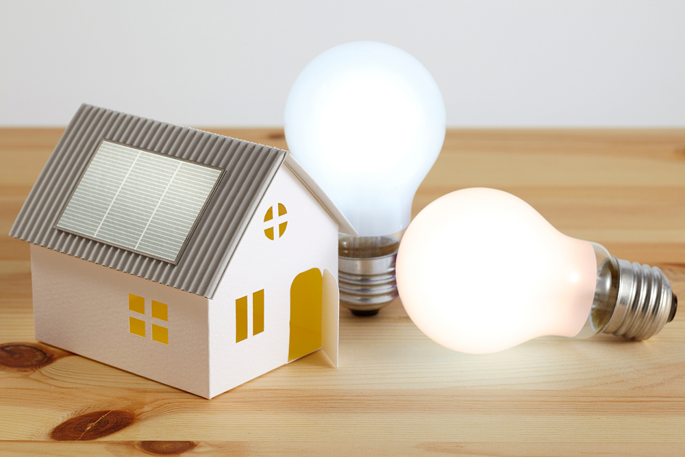 住宅の電気をイメージした電球と家のオブジェ