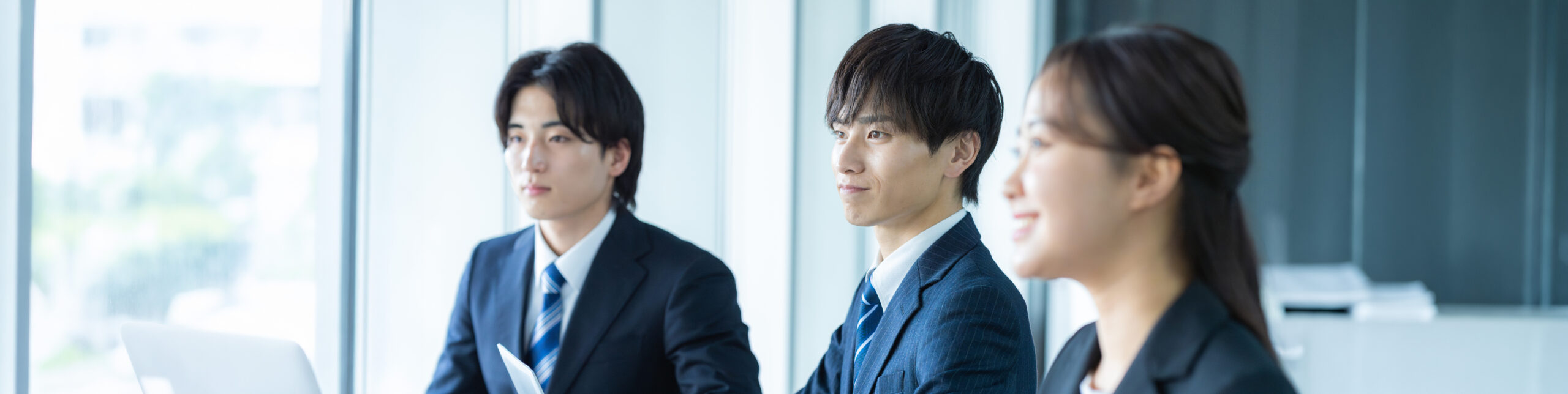 オフィスで上司の説明を聞く新卒社員男女3人